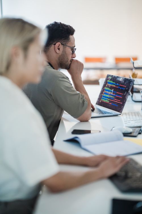 Two software developers work collaboratively on a coding project in a modern office setting. Photo: Pexels.