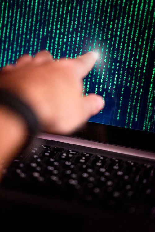 A person pointing at a glowing code interface on a computer screen, representing modern technology interaction. Photo: Pexels.