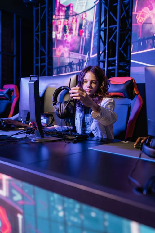 A young player in a gaming chair adjusting their headphones in an eSports arena. Photo: Pexels.