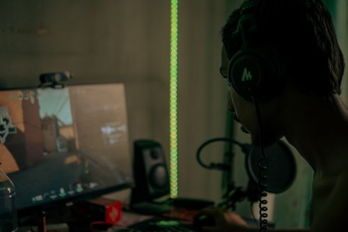 A focused professional gamer playing online with a headset on a desktop computer. Photo: Pexels.